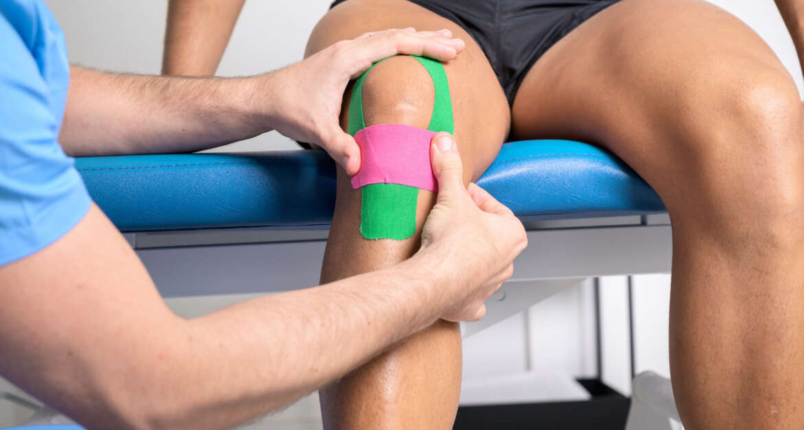 Patient with athletic tape on knee being examined