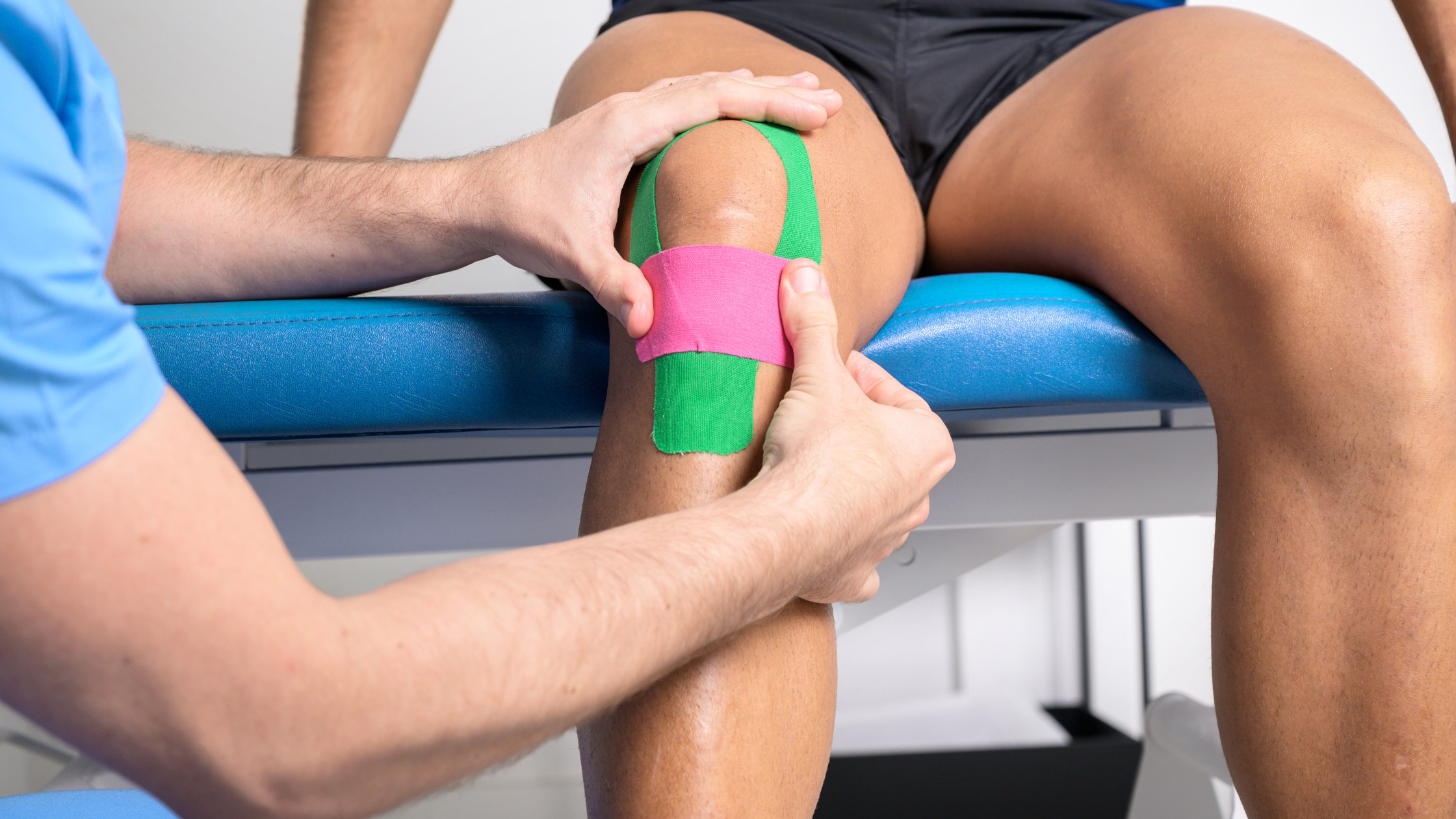 Patient with athletic tape on knee being examined