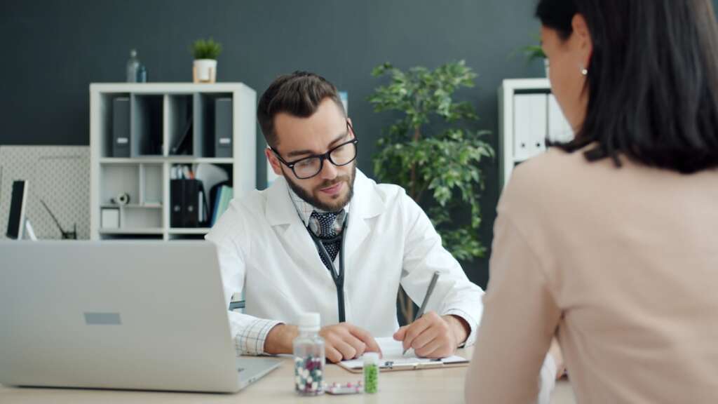Doctor consulting with patient in medical office demonstrating professional healthcare consultation
