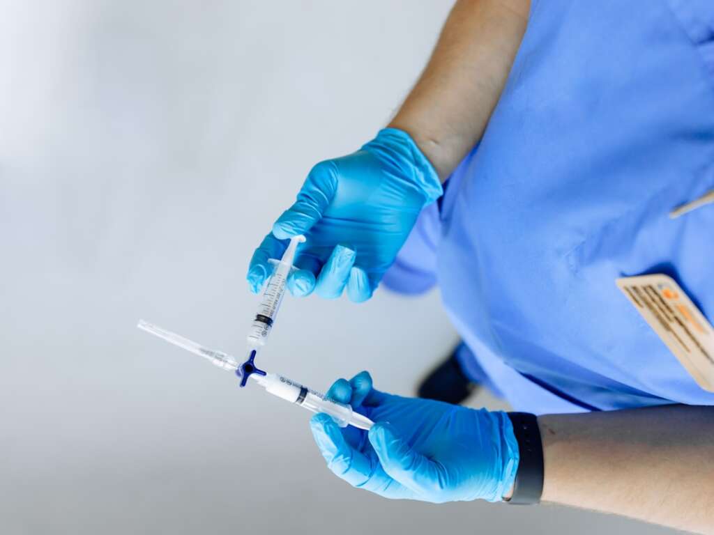 Medical professional in blue gloves preparing injection for pain management therapy