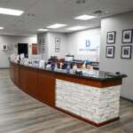 Reception area with curved wooden desk and stone veneer base in a medical office lobby. Barbour Orthopaedic sign on wall behind the desk.