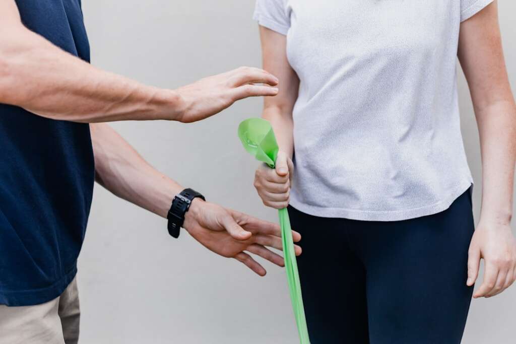 Physical therapist guiding patient through shoulder rehabilitation exercise using resistance band
