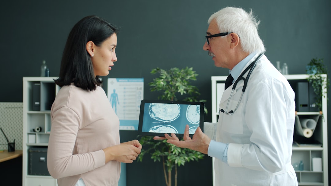 Doctor and patient discussing MRI images on tablet screen in medical office consultation. Photo by Unsplash