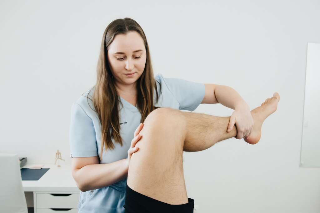 Physical therapist assisting a patient with knee rehabilitation exercises after knee replacement surgery