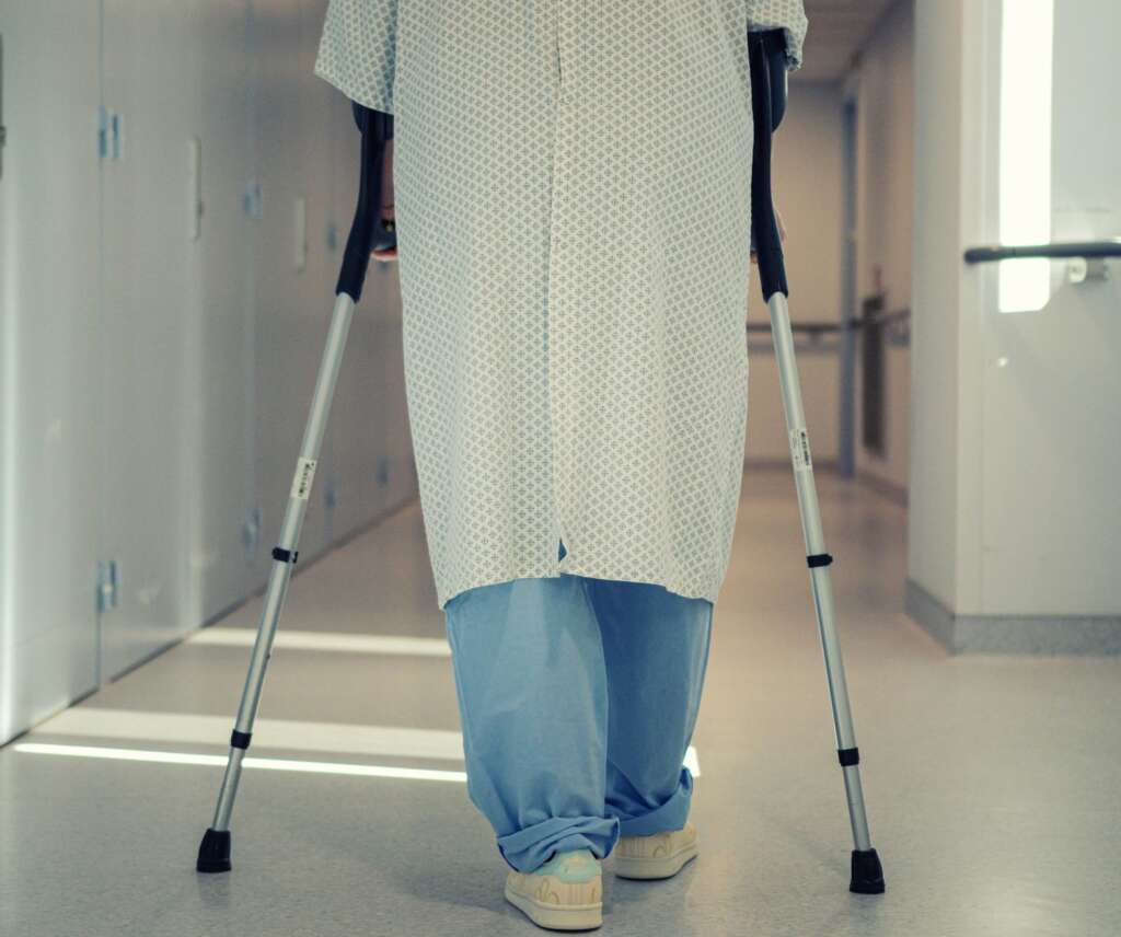 Patient using crutches to walk in a hospital corridor after hip surgery