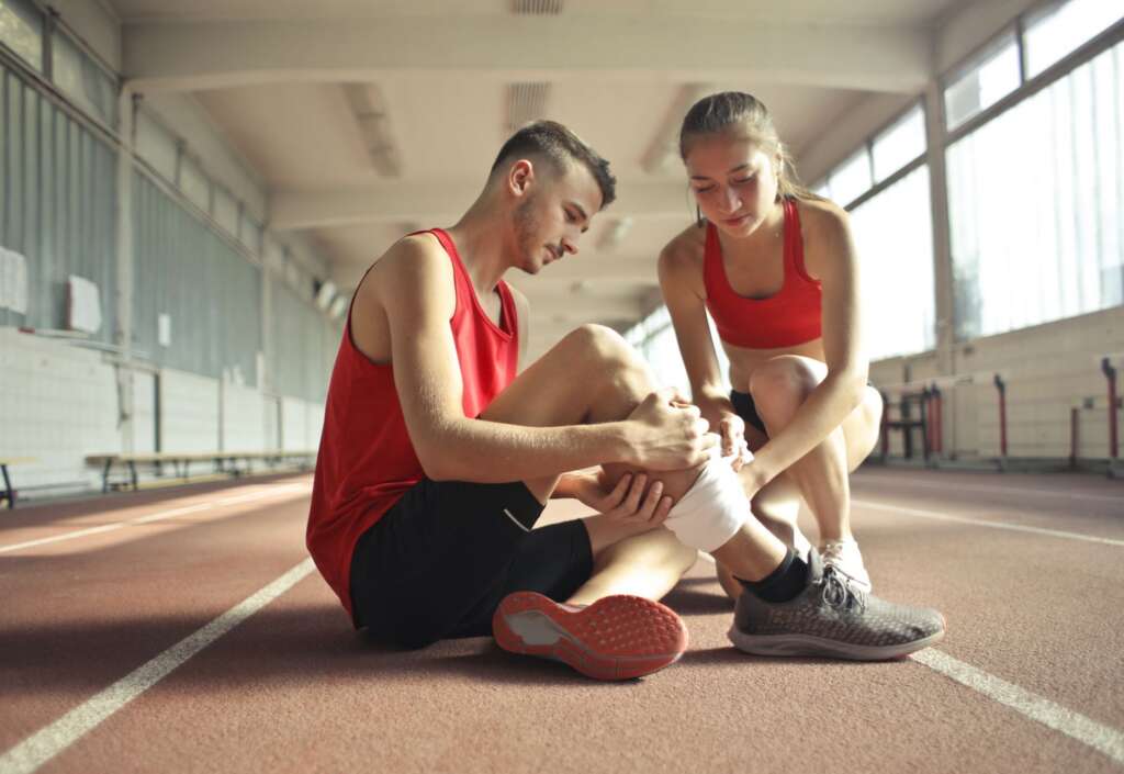 Athletes dealing with sports injury on track, illustrating common sports injuries treated at Barbour Orthopaedics Jacksonville
