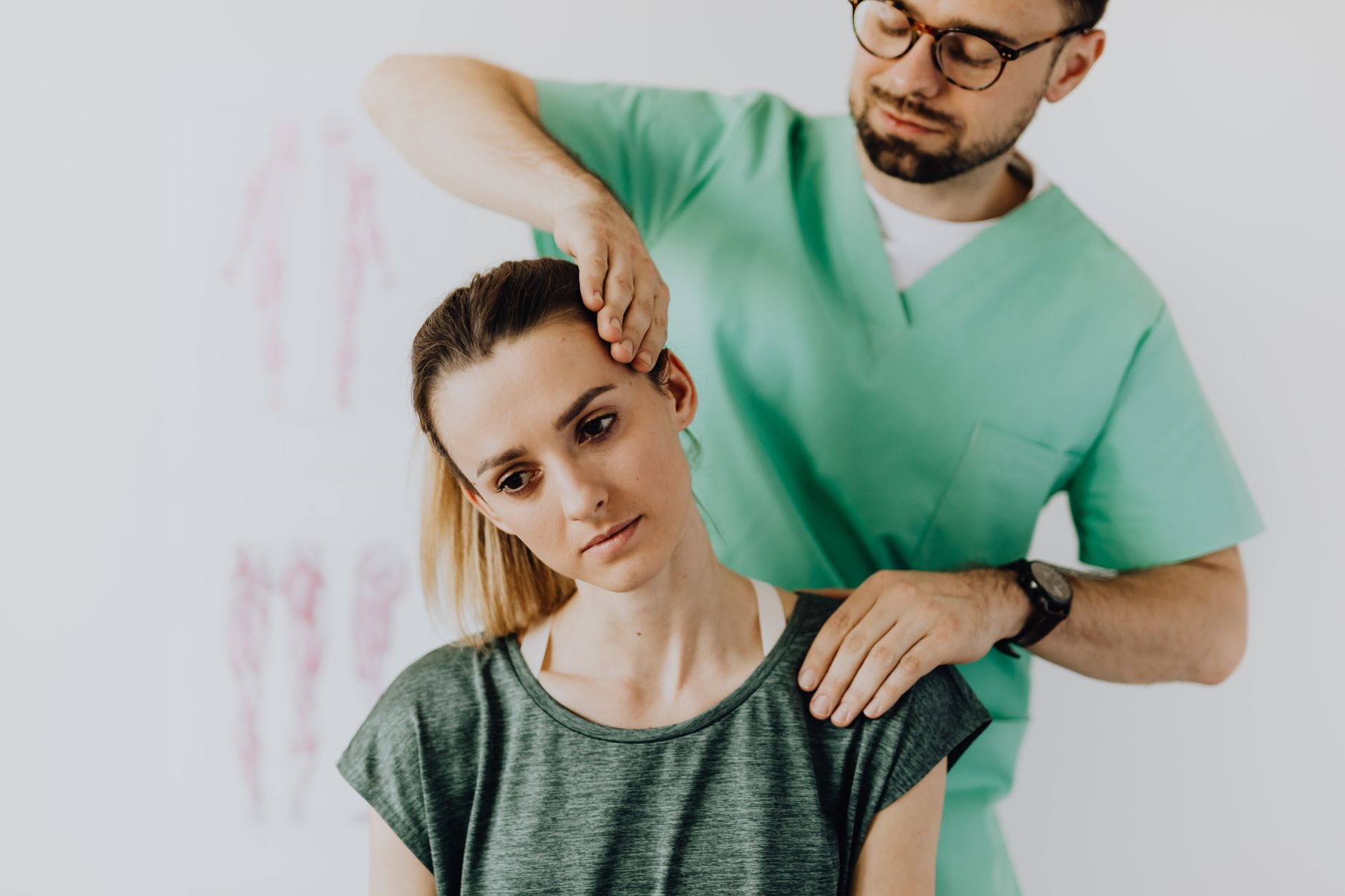 Neck specialist doctor in scrubs examining a patient's neck and cervical spine in a medical office