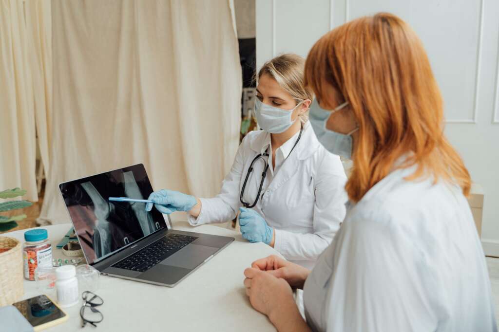 Orthopedic doctor reviewing X-ray images with a patient during a hip replacement consultation