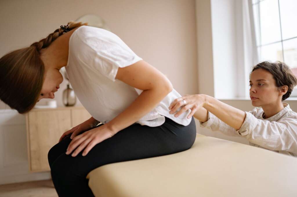 Physical therapist stretching a patient's lower back during a clinical treatment session