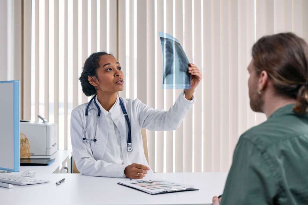 Female doctor reviewing an X-ray with a male patient during a first consultation at a spine specialist's office