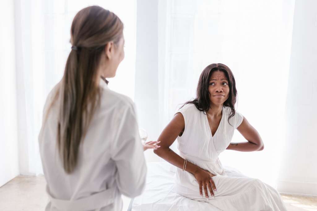 Woman experiencing back pain during a consultation with her doctor