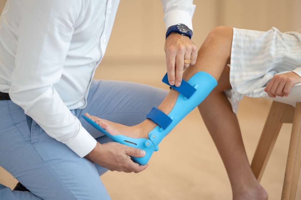 Healthcare professional fitting an ankle-foot orthosis on a patient — orthopaedic treatment